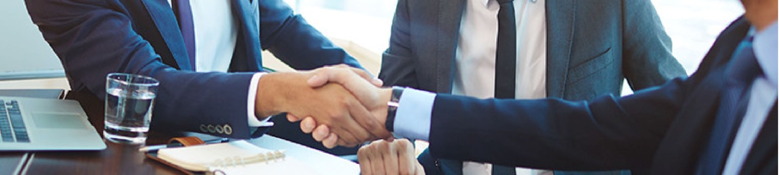 three people in a meeting shaking hands in agreement