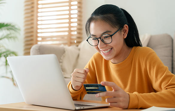 Person holding debit card shopping on laptop.