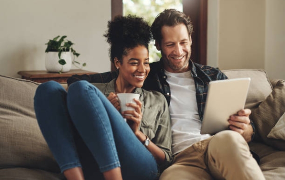 A couple sitting on a couch with their tablet