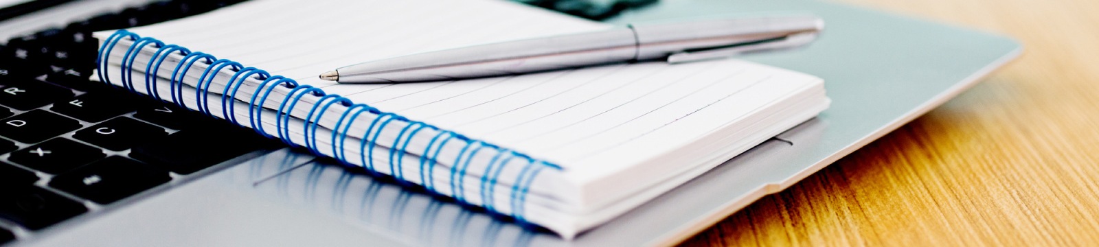 a pen and note pad laying on a laptop keyboard